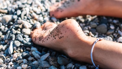 Una mujer con los pies en la playa.