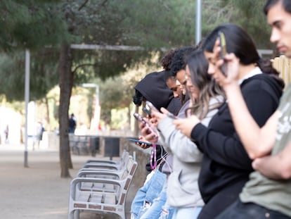 Varios jóvenes con sus teléfonos móviles en la mano.