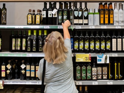 Una clienta de un supermercado español elige una botella de aceite de oliva.