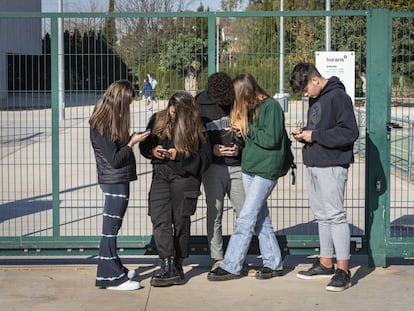 Un grupo de adolescentes consulta sus móviles a las puertas de un centro educativo de Valencia.